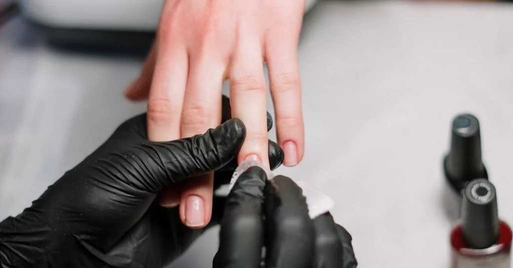 Close-up of a professional manicure with gel polish and black gloves in a salon.