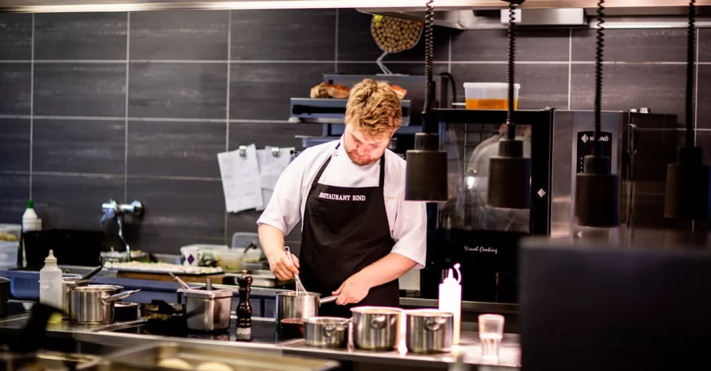 Chef preparing meal in a modern kitchen with various cookware.