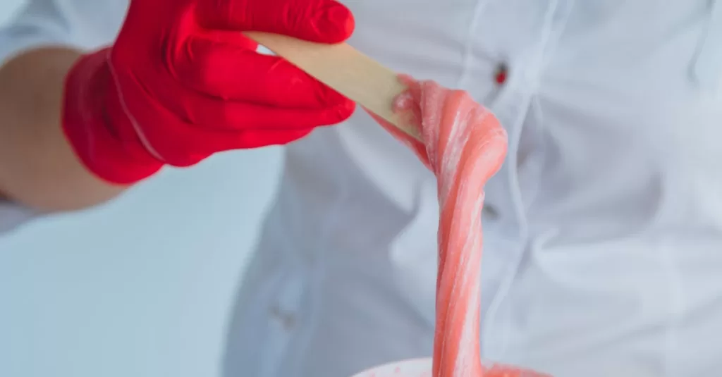 Close-up shot of a sugaring expert applying paste, showcasing cleanliness and precision.